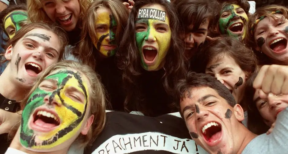 Imagem de jovens com rosto pintado de verde e amarelo, segurando faixa escrito "impeachment já", e uma jovem com uma faixa na testa escrito "fora Collor".