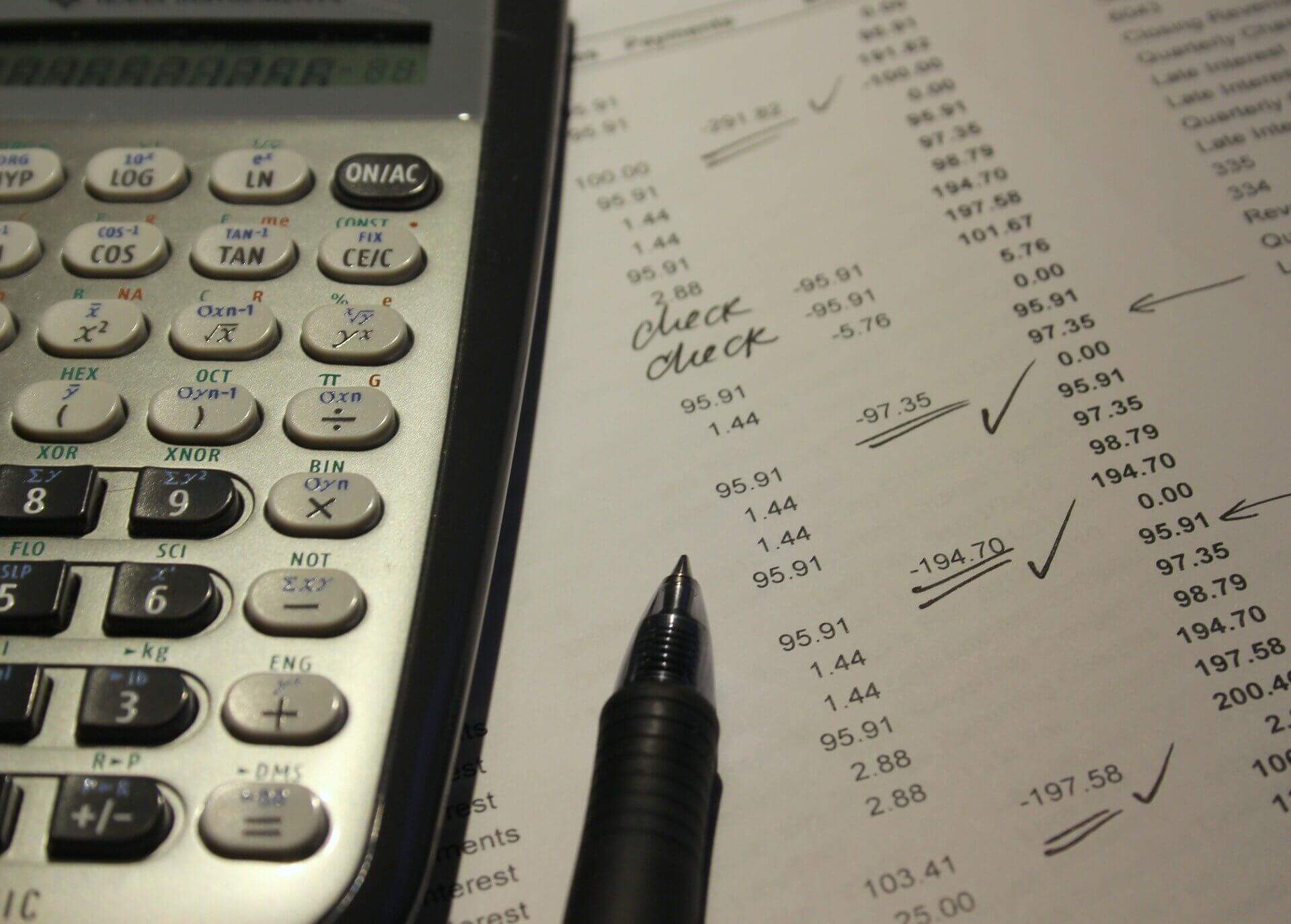 Na imagem, calculadora e uma caneta sobre uma folha. Conteúdo sobre isenção fiscal, alíquota zero e imunidade tributária.