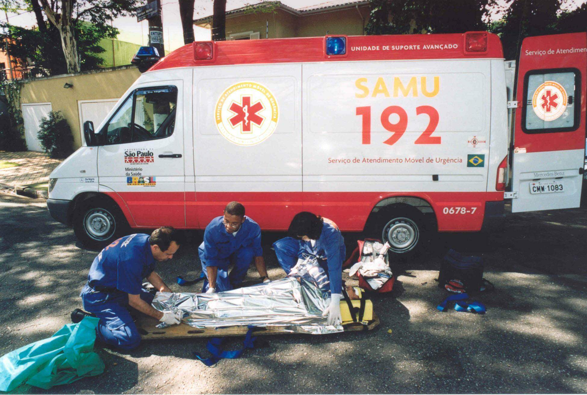 Foto de paramédicos e ambulância do Samu.