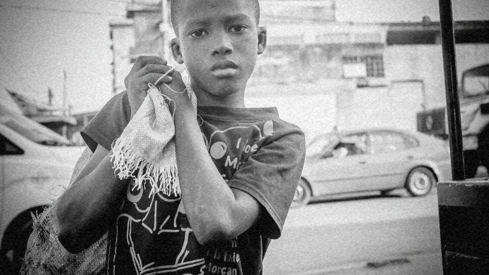Imagem de uma criança na rua carregando uma rede nas costas com aspecto de tristeza representando as medidas socioeducativas e os desafios dos direitos das crianças