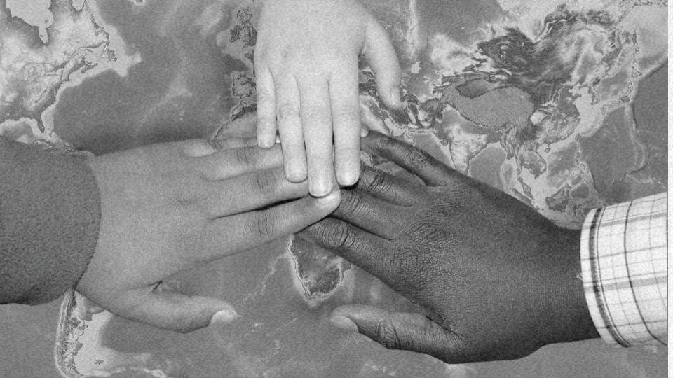 Imagem mostrando a mão de três pessoas unidas com o mundo de fundo representado o que são os direitos humanos