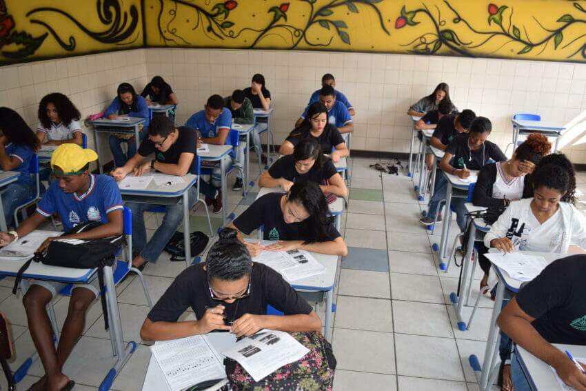 Na imagem, estudantes sentados fazendo um simulado na escola. Conteúdo sobre Plano Nacional de Educação