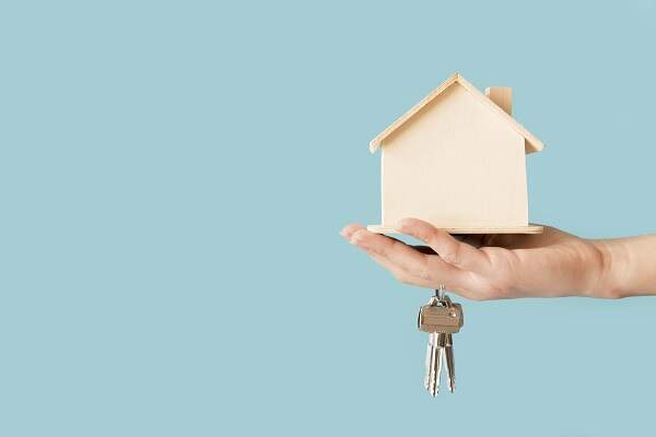 Mão carregando as chaves de uma casa e uma miniatura de uma casa, feita de madeira | Desapropriação – Artigo Quinto