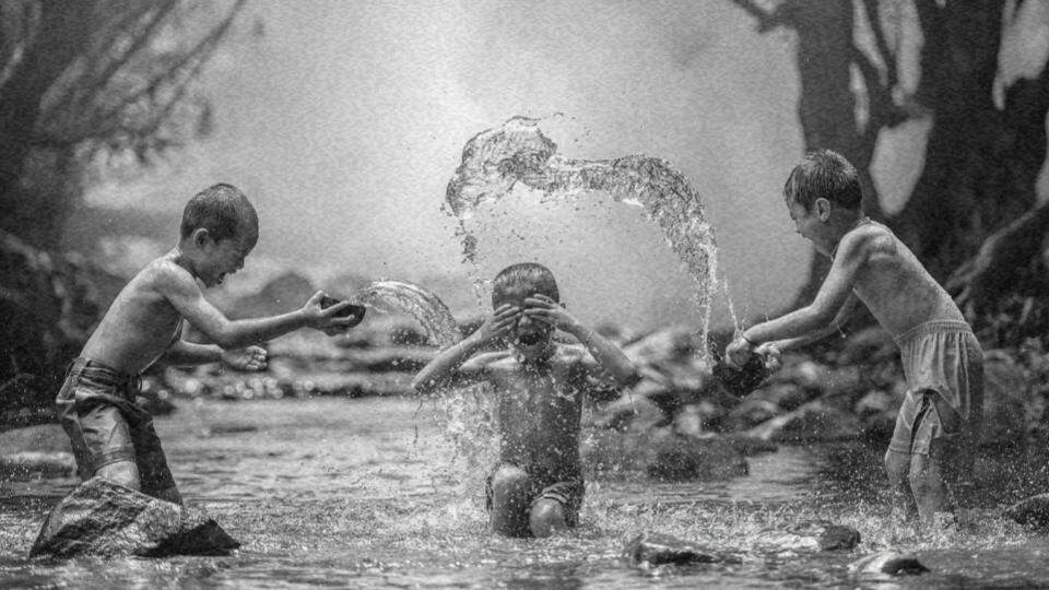 Imagem de três crianças brincando no rio representando os direitos das crianças e dos adolescentes