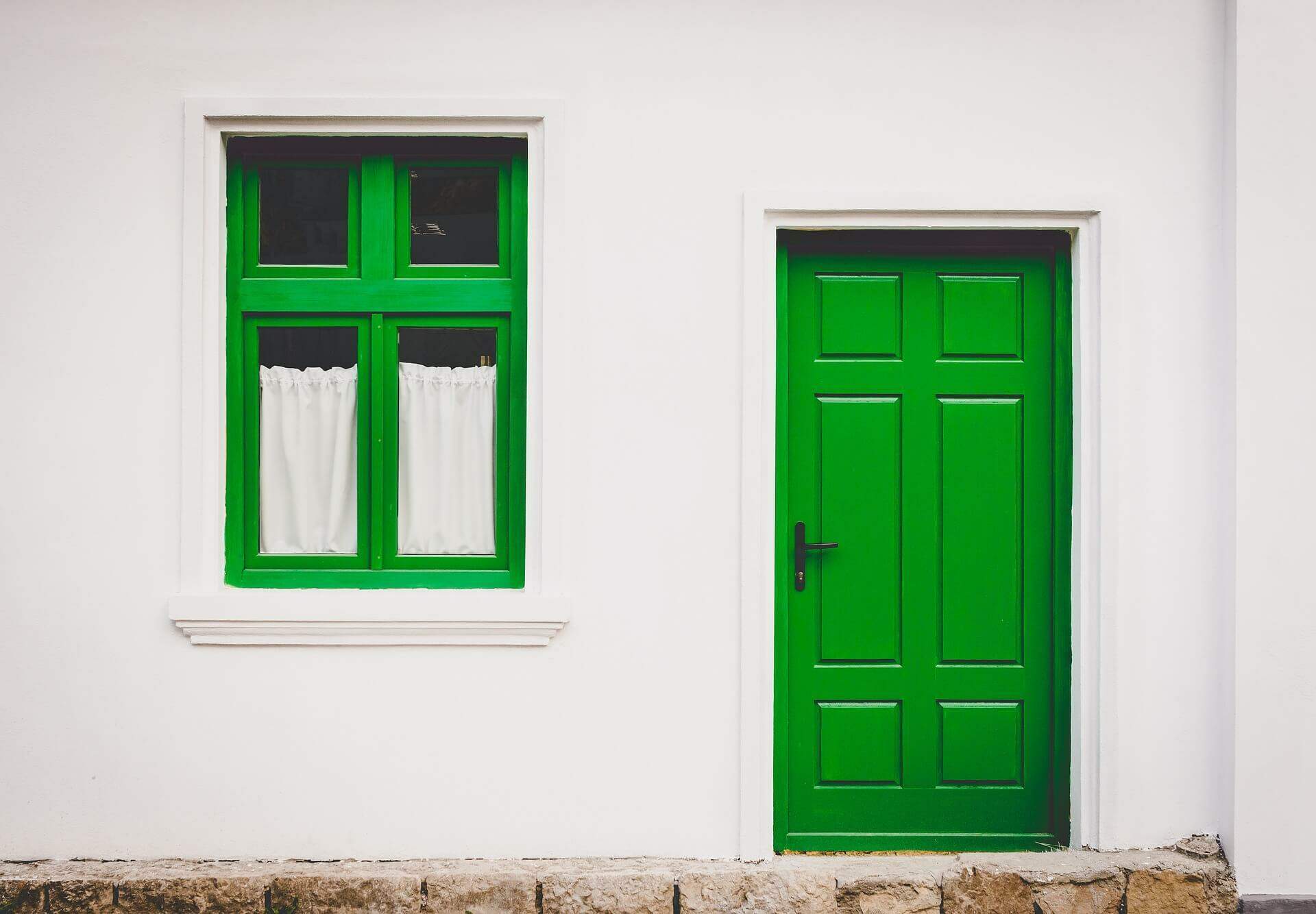 Imagem de uma casa branca, com porta e janela verde | Função social da propriedade – Artigo Quinto