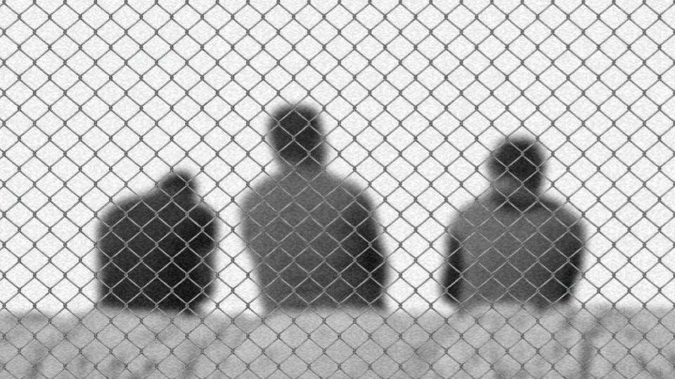 Imagem de três homens atrás de grades que impedem a sua passagem representando os migrantes e refugiados no Brasil e quais os seus direitos