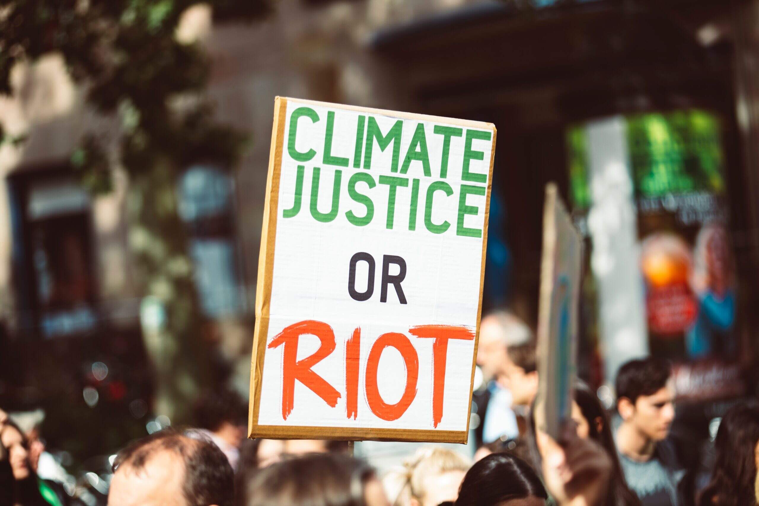 Placa "climate justice or RIOT"