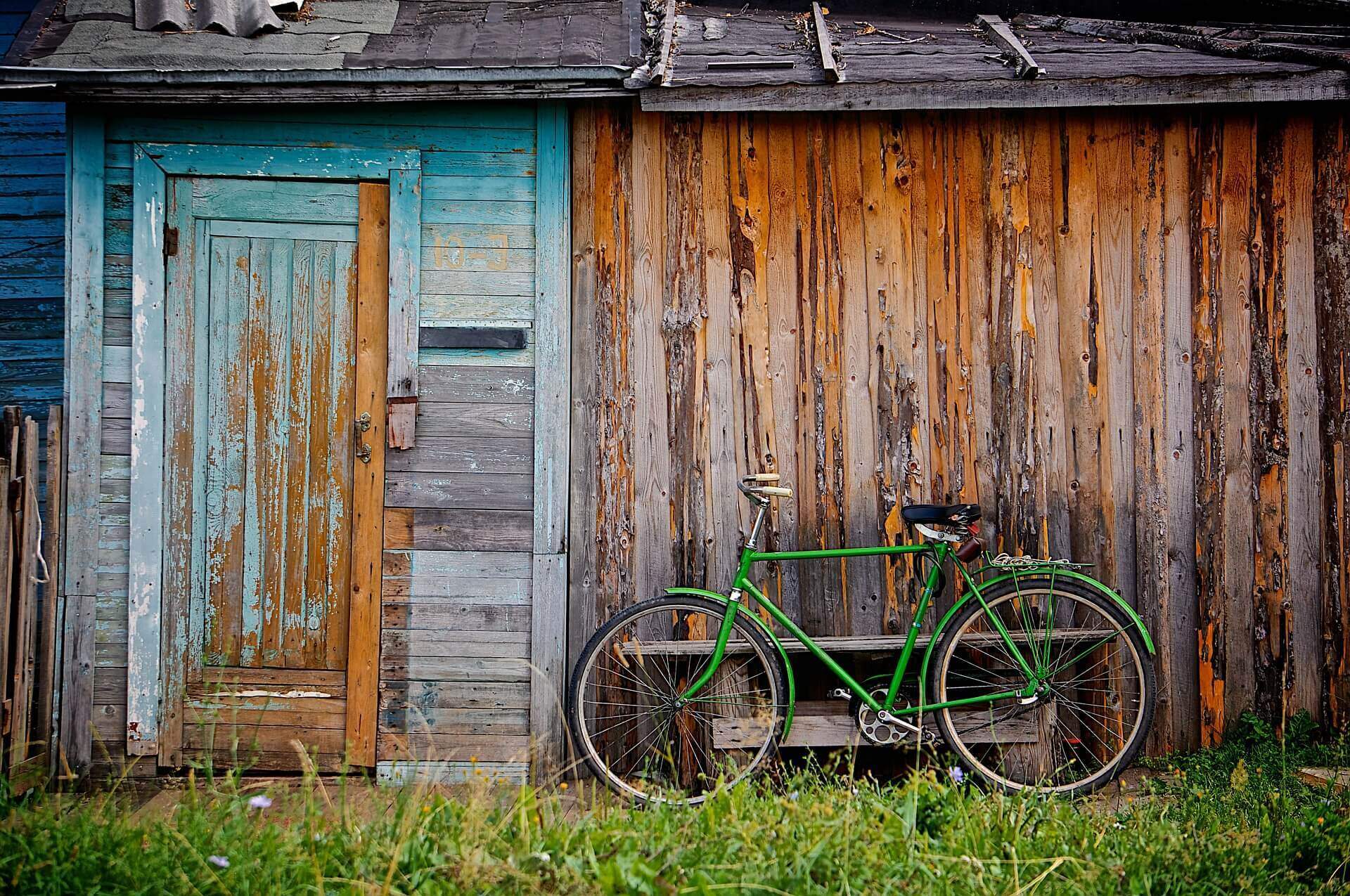 Casa de madeira, já antiga, com uma bicicleta verde encostada na mesma | Função social da propriedade – Artigo Quinto