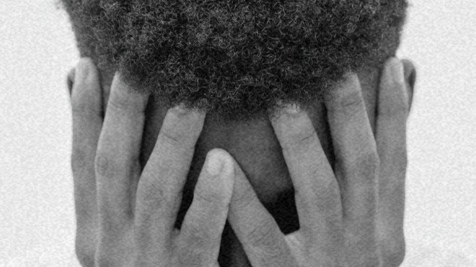 Imagem de um homem negro de cabeça baixa representando a violência racial no Brasil e no mundo