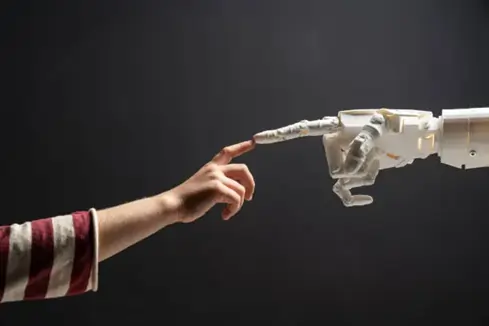 Imagem de uma mão humana e uma mão robótica se tocando. Texto: Geração Beta: a nova era da inteligência artificial embutida