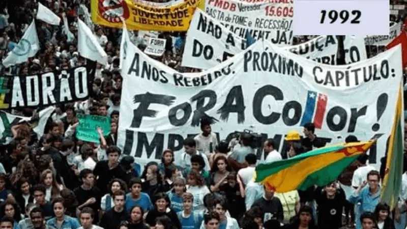 Imagem de várias pessoas na rua, especialmente jovens, manifestando nas ruas contra collor. Carregam faixas com escritos como "fora collor" e "ladrão"