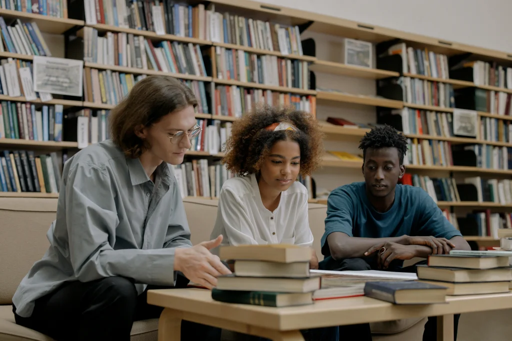 Estudantes concentrados em uma biblioteca, rodeados de livros, preparando-se para a prova da OAB.