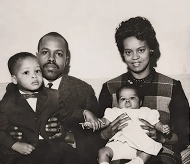 Um homem e uma mulher negros, segurando um menino e uma bebê, também negros. 
