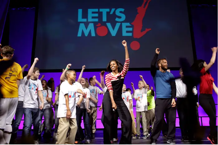 Imagem do evento Let's Move, várias pessoas em cima de um palco com as mãos pra cima, estão se movimentando com alegria.
