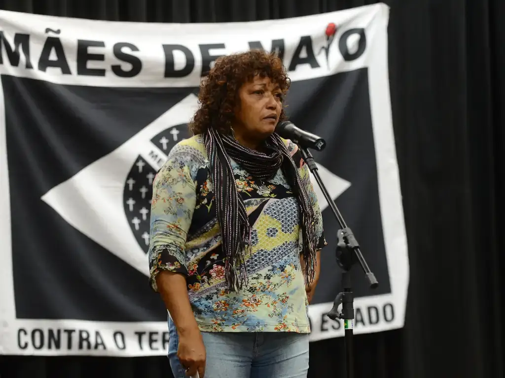 A imagem mostra Débora Silva, coordenadora do Movimento Mães de Maio, falando em um evento público