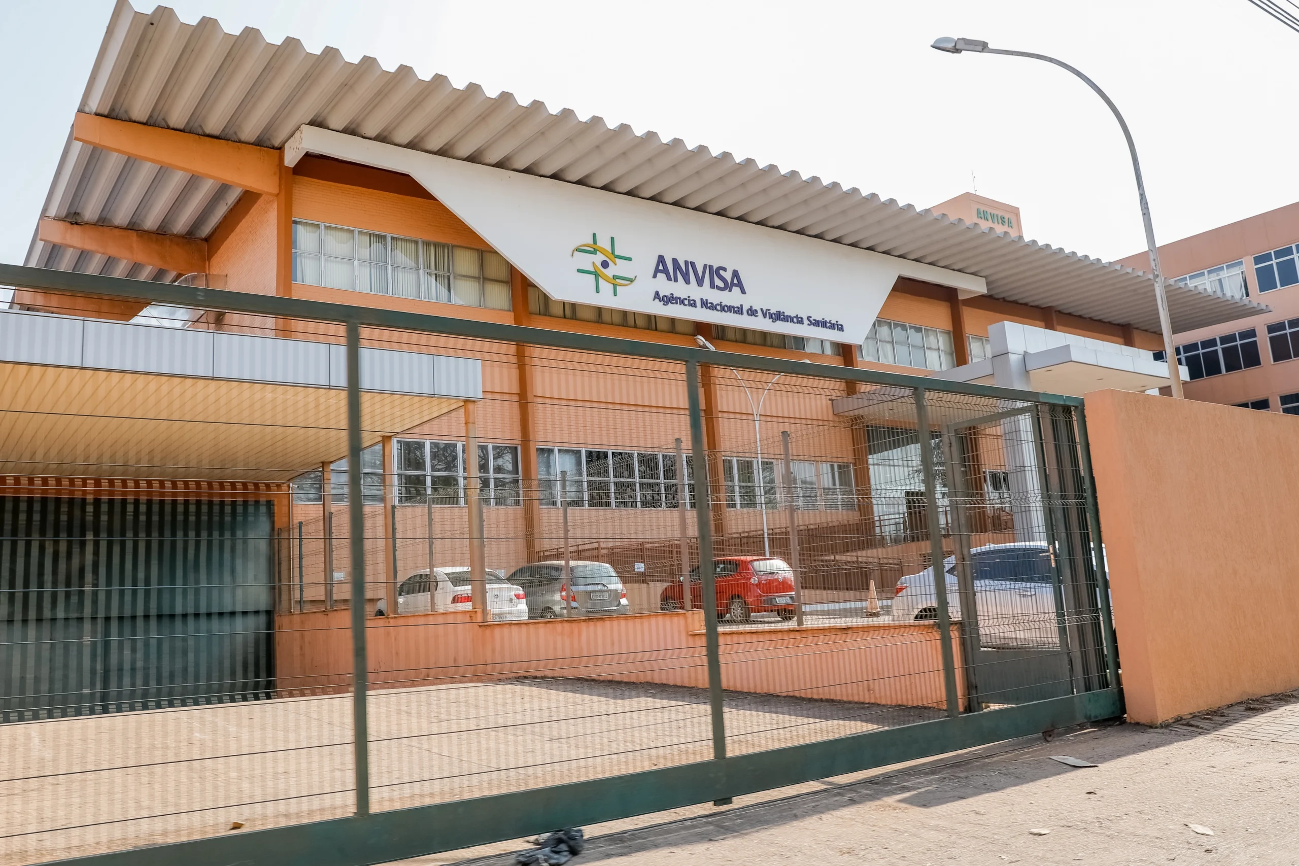Fachada do edifício sede da Anvisa, em Brasília, com fachada de cor laranja e faixa branca com o nome da instituição.