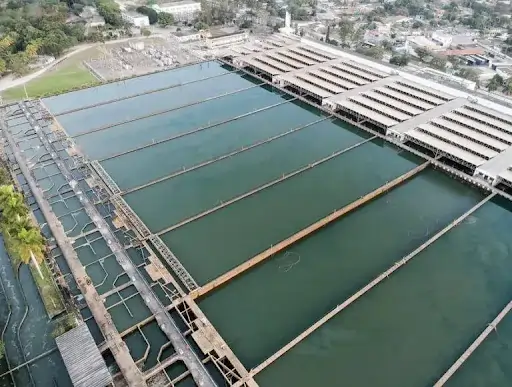Imagem de uma grande estação de tratamento de água, ao dia, várias barragens em meio a uma área restrita com água. Texto: Política Nacional de Recursos Hídricos: o que é e qual sua importância para o meio ambiente?