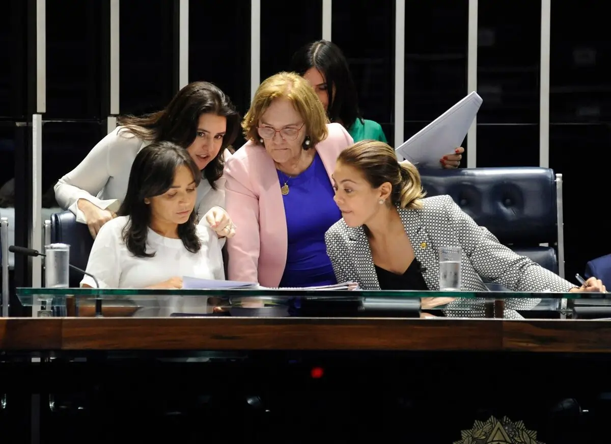 Foto de parte da bancada feminina do Senado discutindo sobre pauta legislativa, sentadas à mesa. Texto: Cota de gênero no novo código eleitoral: o que está em debate?
