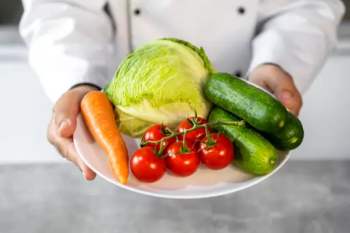 Fotografia de uma pessoa oferecendo um prato de alimentos saudáveis variados. Texto sobre segurança alimentar.