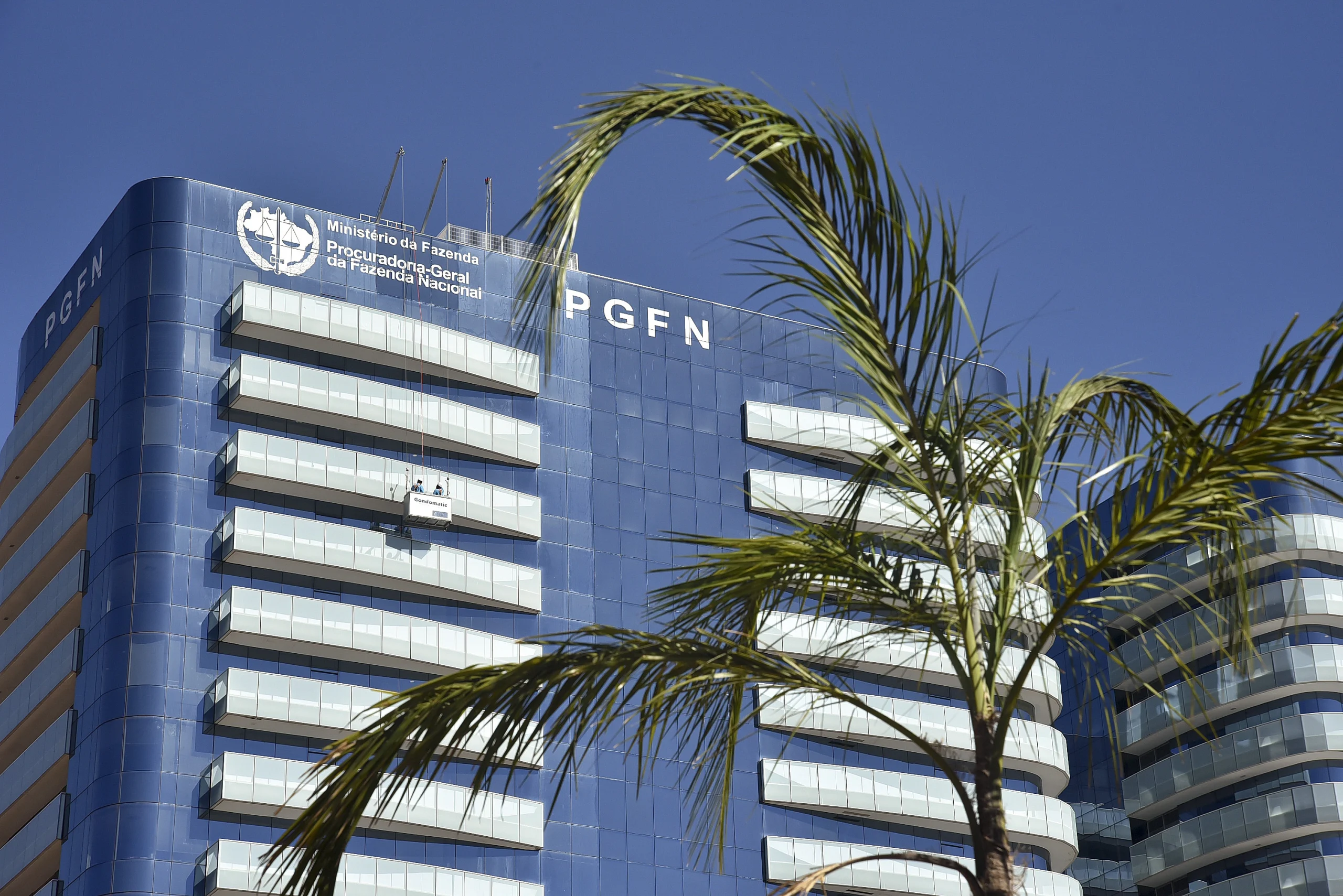 Edifício moderno da PGFN em Brasília, com fachada em tons azuis, vidros espelhados e a sigla PGFN em destaque.